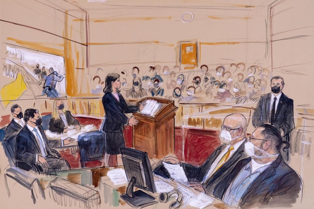 This artist sketch depicts Guy Wesley Reffitt, bottom right, joined by his lawyer William Welch, third from right, listening as prosecutor Risa Berkower, speaks at the podium at center, as a video depicts a handgun on the waist of Reffitt, at left