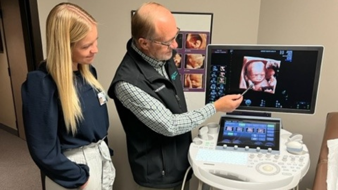 Vrbicky pointing to one of his future patients. The Norfolk obstetrician-gynecologist who has delivered 13,000-plus babies in the area returned to work four months after his heart transplant.