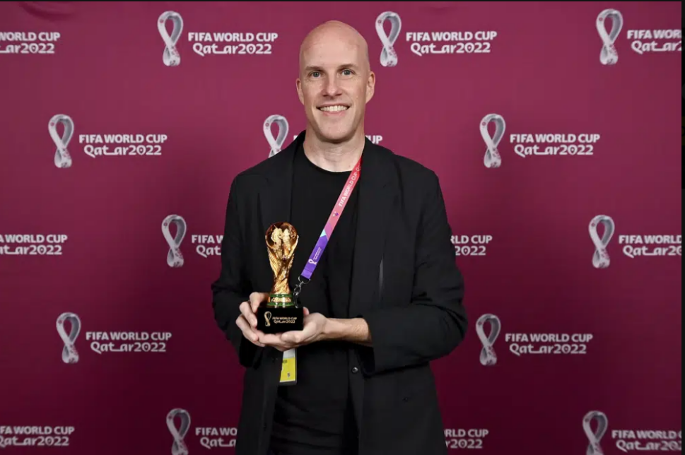 Grant Wahl smiles as he holds a World Cup replica trophy during an award ceremony in Doha, Qatar on Nov. 29, 2022.