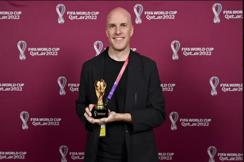 Grant Wahl smiles as he holds a World Cup replica trophy during an award ceremony in Doha, Qatar on Nov. 29, 2022.