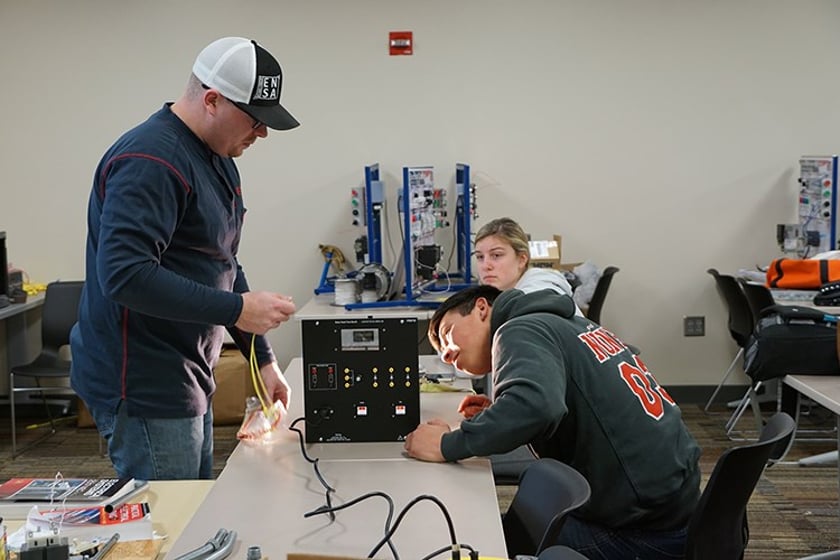 Taylor Schneider, energy technology instructor at Central Community College, helps students work on a wind turbine motherboard.
