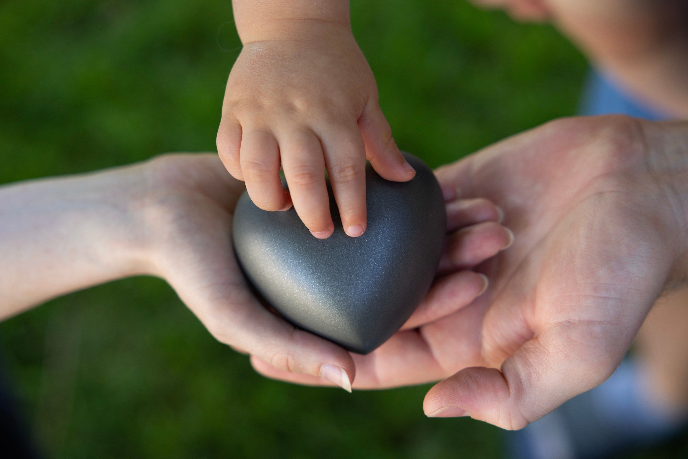 Zoe, her husband and 20-month-old son cradle the heart-shaped urn holding the cremated remains of her son, Skye on Friday, June 21, 2024, in Omaha, Neb.