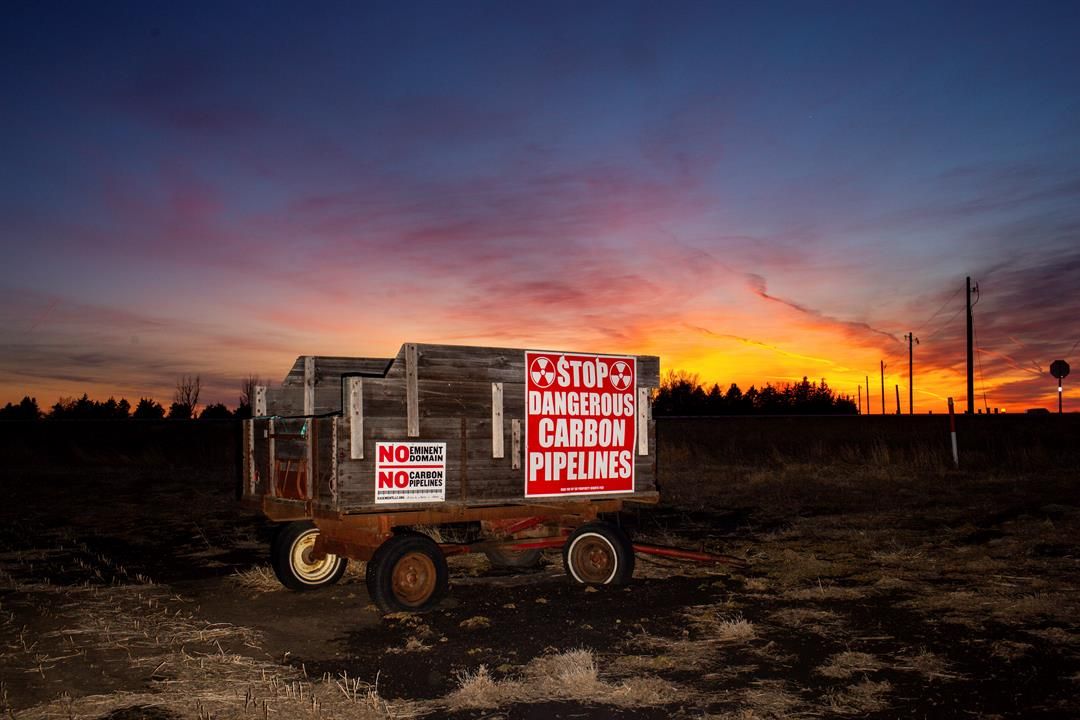 A wagon covered in signs protesting the installation of a Summit Carbon Solutions pipeline stands on a farm in Lake County, S.D., on Monday, March 10, 2025, in one of the counties that the pipeline would cut through. (AP Photo/Nicole Neri)
