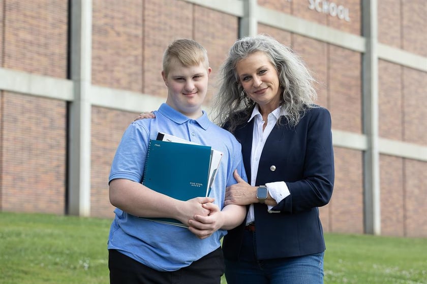 Dylan Zephier, known as “D” to his friends and family, stands with his mother Michele outside of Lincoln East High School. Dylan, who has Down syndrome and autism, will start his senior year in the fall. Photo by Liz McCue for the Flatwater Free Press