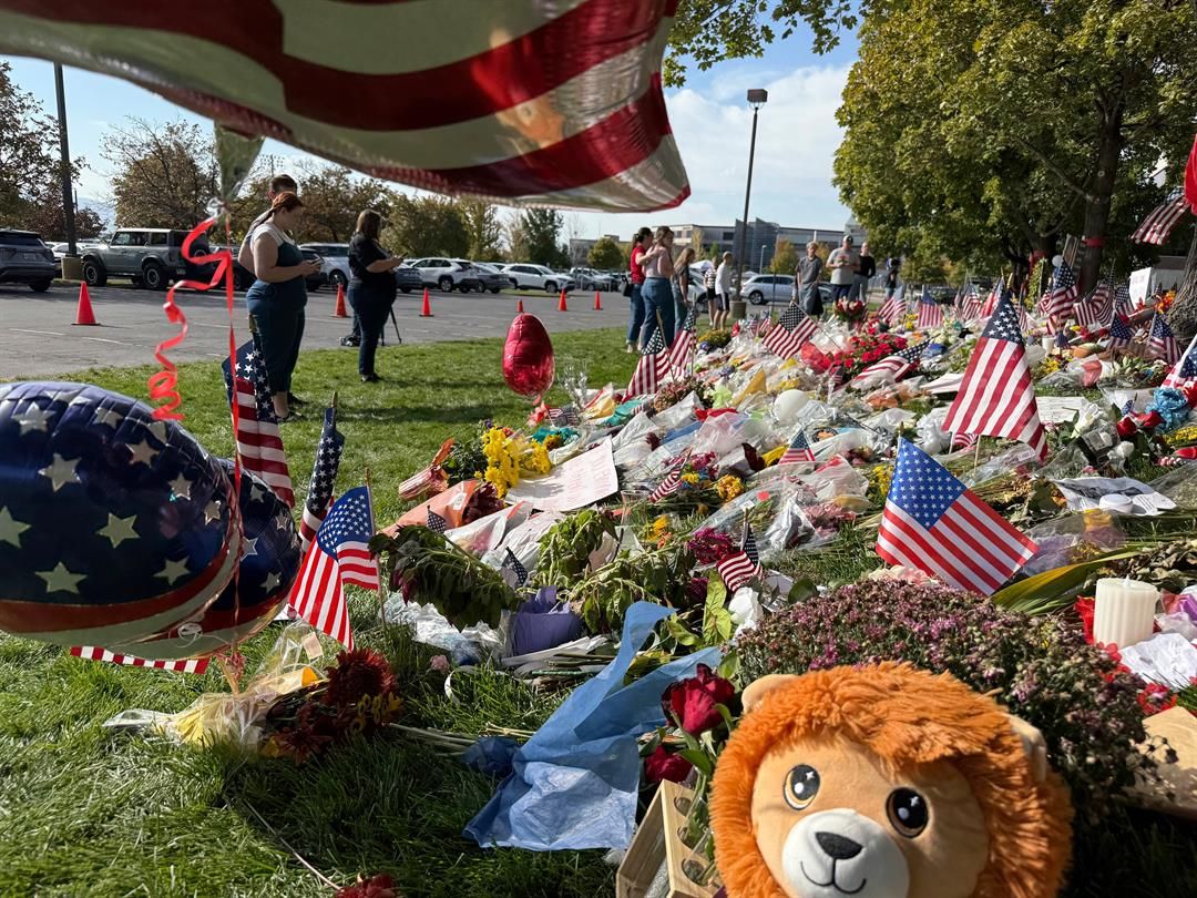 People bring flowers and write messages in chalk at a memorial for Charlie Kirk at Utah Valley University, on Monday, Sept. 15, 2025, in Orem, Utah. (AP Photo/Jesse Bedayn)